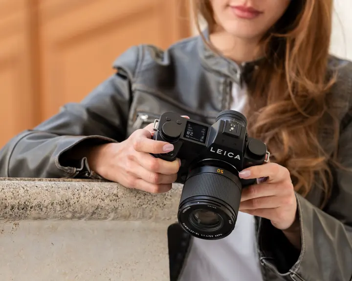 Close-up of a photographer adjusting a Leica camera.