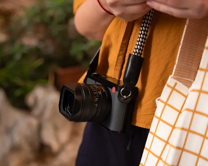 Person carrying a Leica camera while exploring outdoors