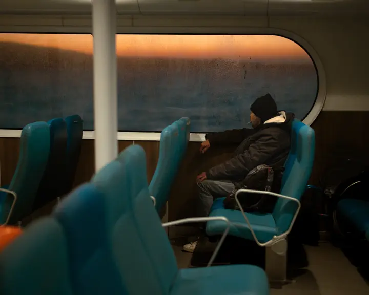 Un homme assis dans un bateau, une cigarette à la bouche.