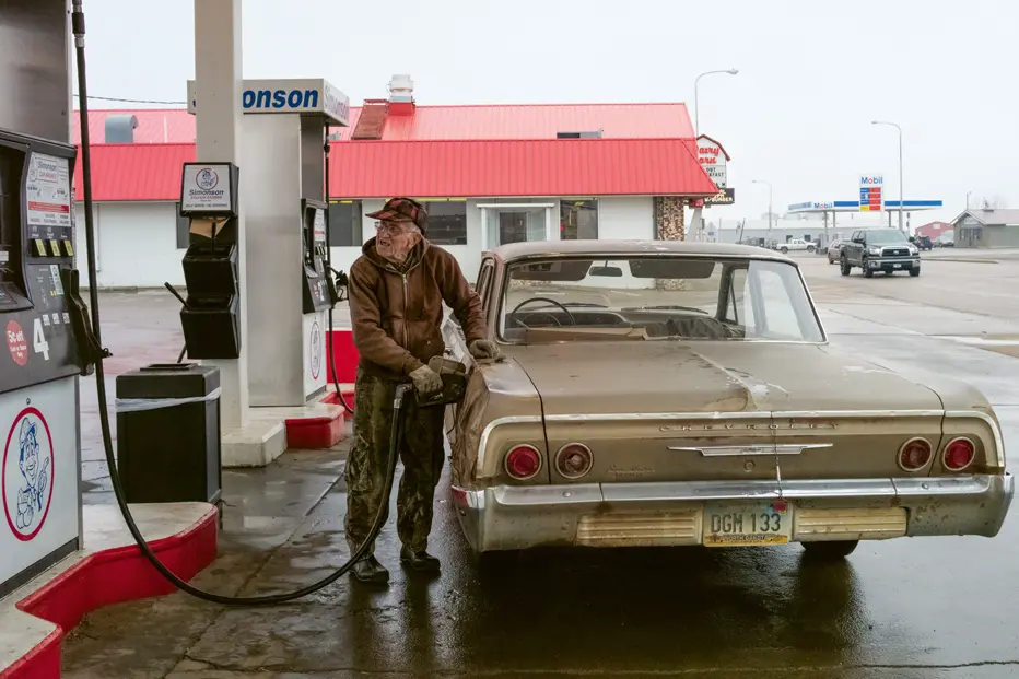 Old man filling up his Chevrolet on a gas station