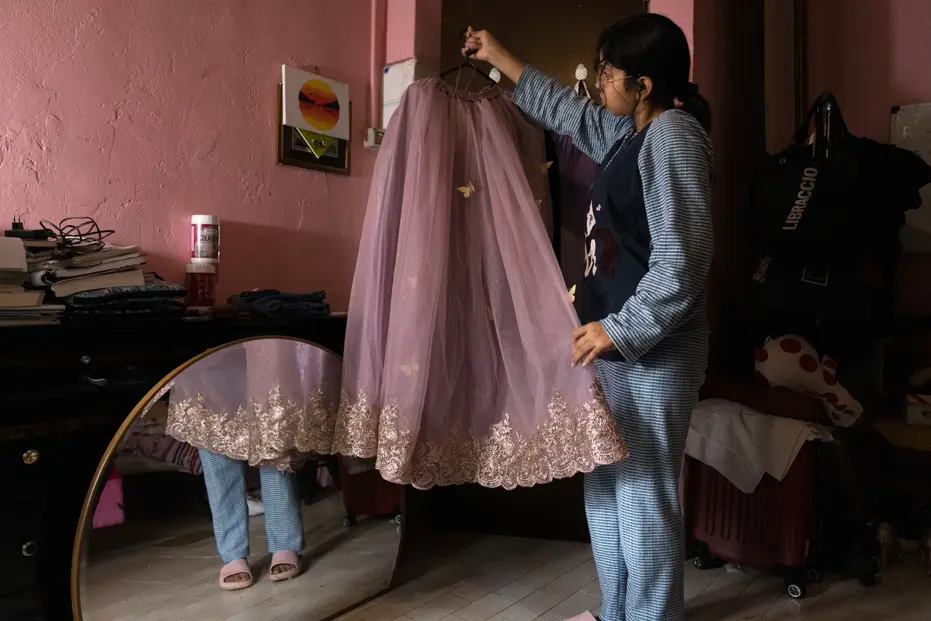 Young woman preparing a lavender quinceañera dress at home, capturing anticipation, family traditions, and a milestone celebration.