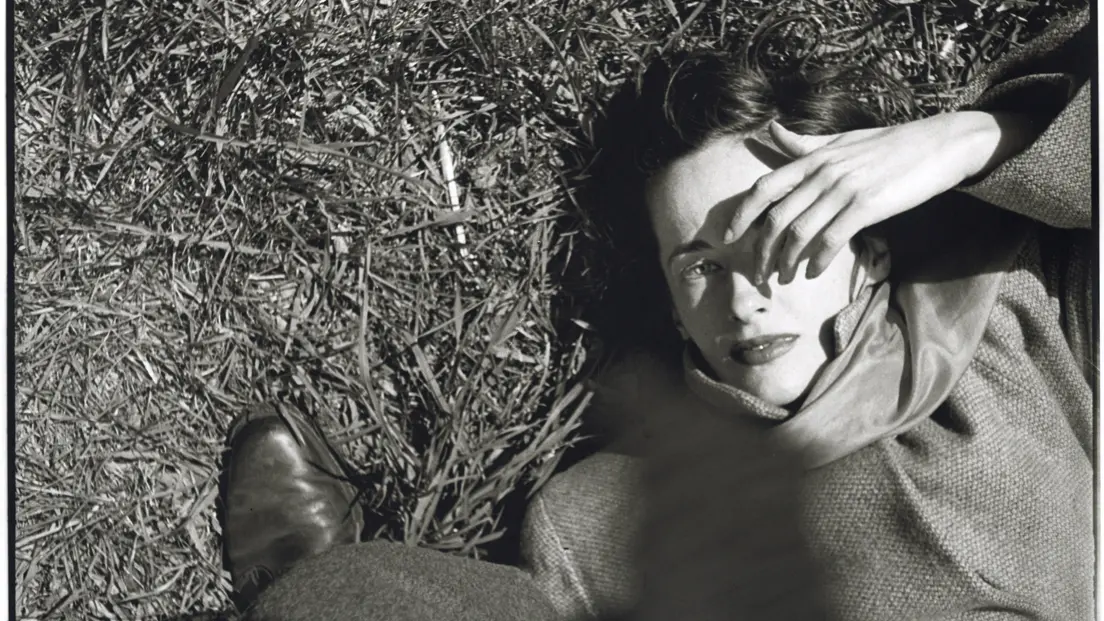 Frau liegt im im Gras und hält sich Hand ins Gesicht, Saul Leiter