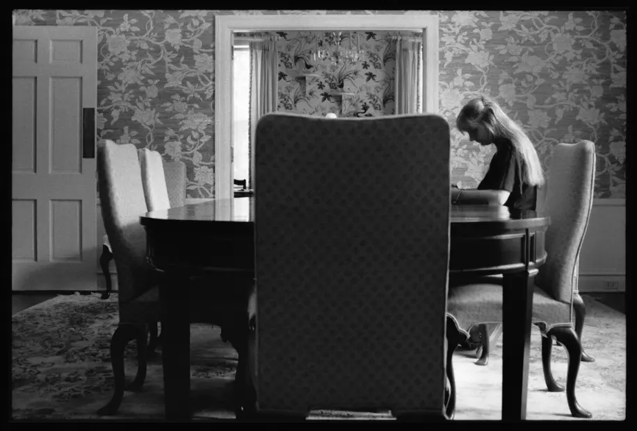 Self-portrait at the dining room table on her family’s cotton farm in Arkansas. Black-and-white analog photograph from Lisa McCord’s long-term documentary series “Rotan Switch.”