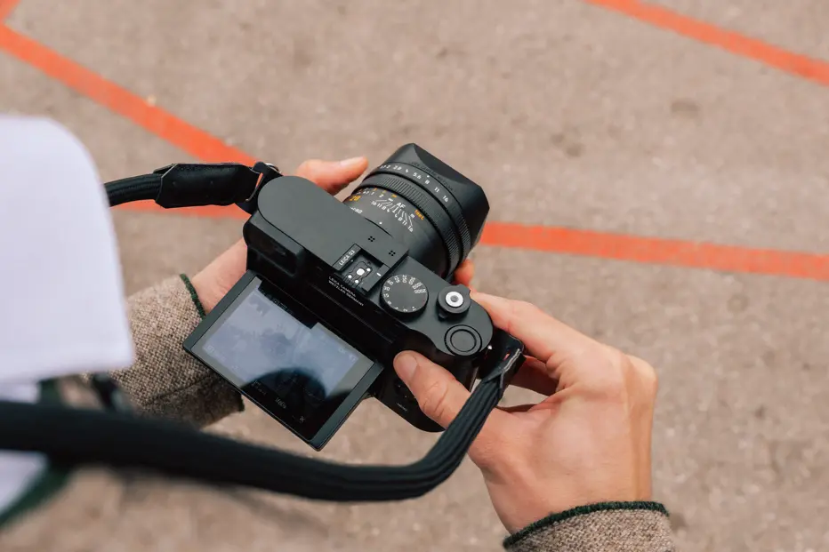 Close-up of a photographer adjusting a Leica Q3 with a Summilux 28 mm lens at Munich Oktoberfest.