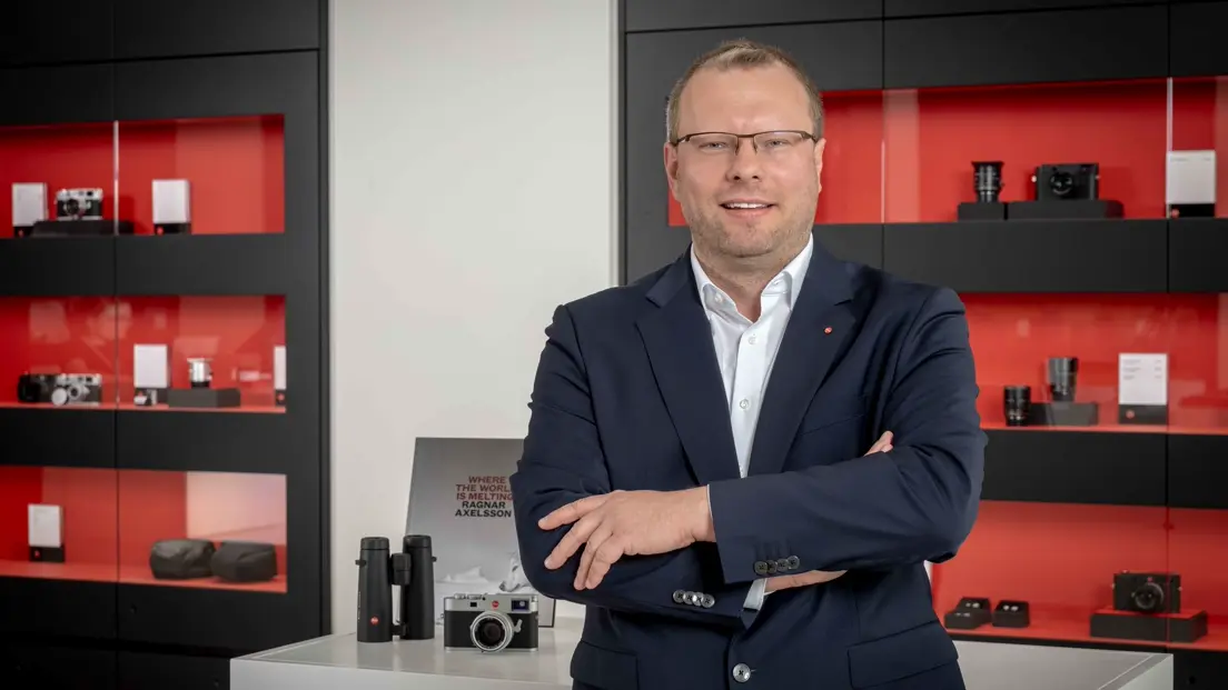 Portrait of Dr. Ronny Fritsche in front of a camera display cabinet.