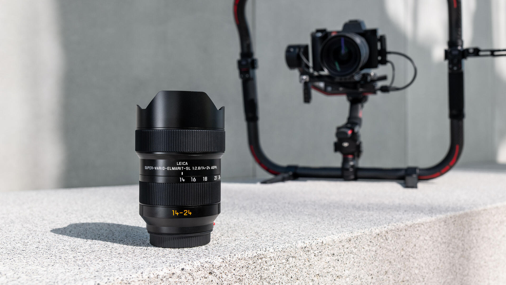 Leica Super-Vario-Elmarit-SL 14-24 f/2.8 ASPH. stands in front of a Leica SL2-S with a Leica Super-Vario-Elmarit-SL 14-24 f/2.8 ASPH. in a gimbal cage.