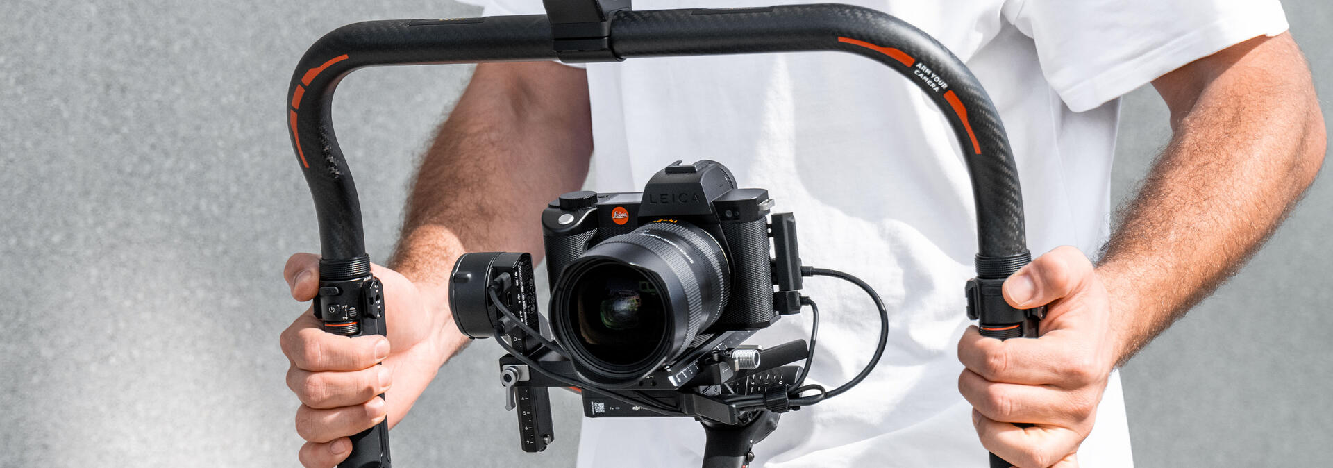 Two arms holding a gimbal cage with a Leica SL2-S with a Leica Super-Vario-Elmarit-SL 14-24 f/2.8 ASPH.