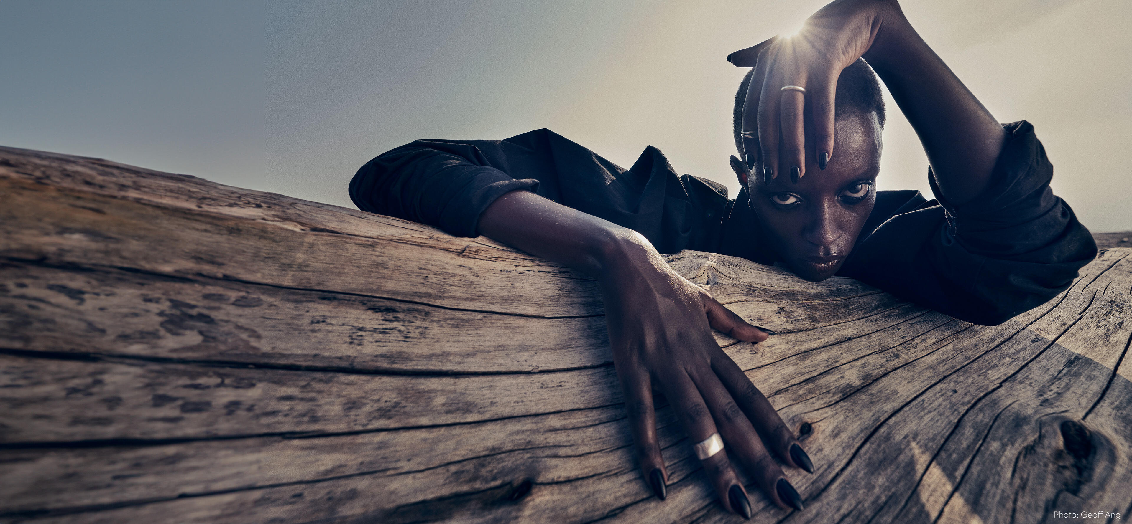 black woman lying on a piece of wood