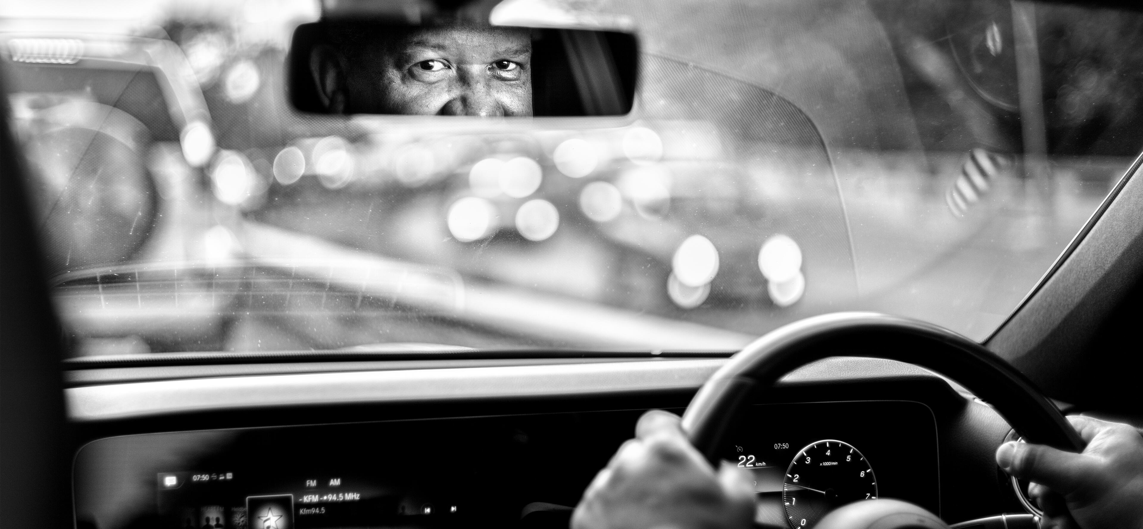 Photo of a car driver looking intently in the rear-view mirror