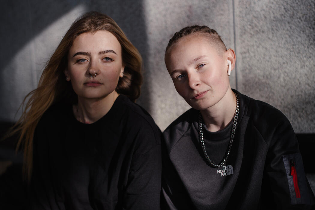 Two women sitting together and looking directly at the camera.