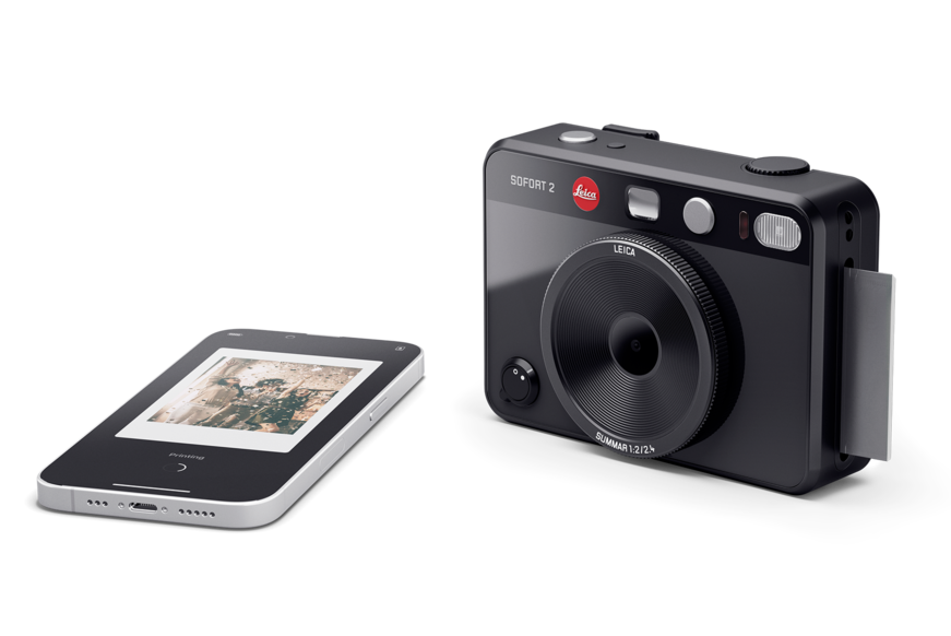 Leica Sofort 2 black beside mobile phone.