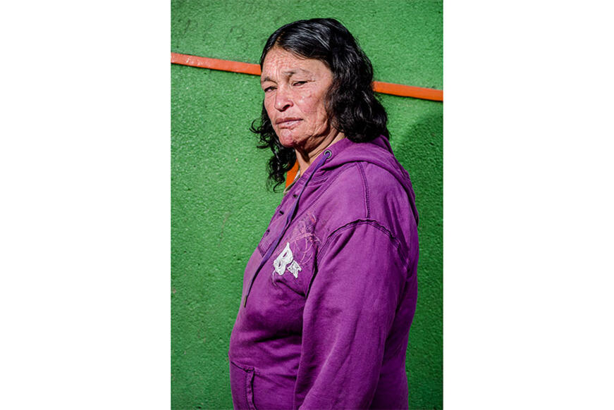 Woman with a purple jacket in front of a green wall