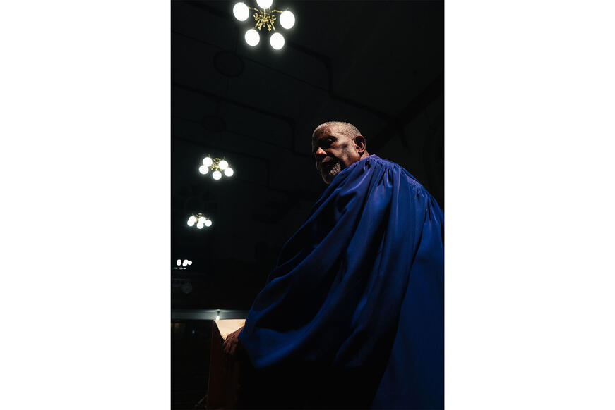 Man with blue robe with lights in the background