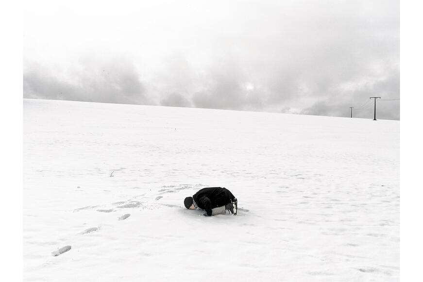 Young adult laying in snow.