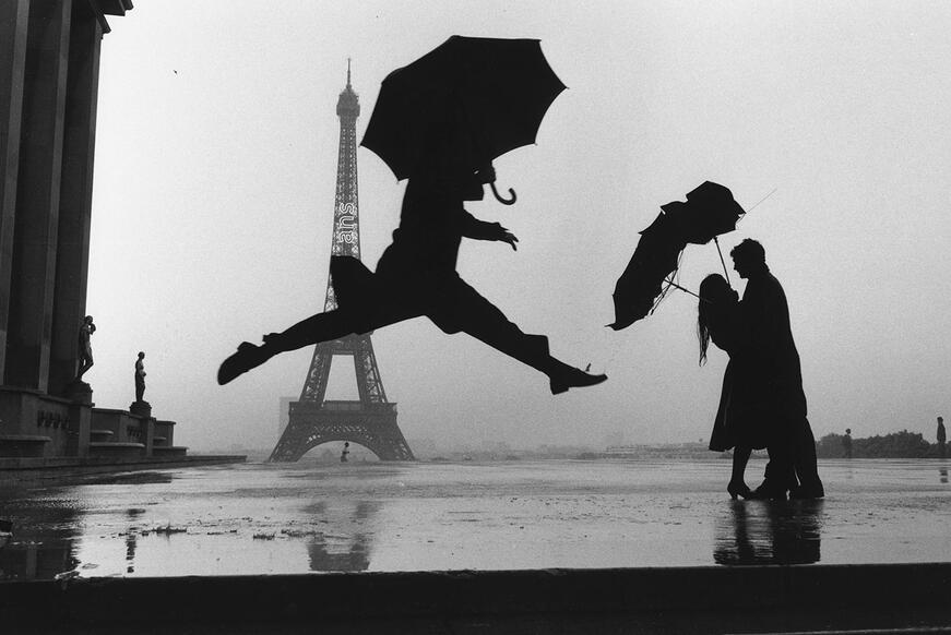 Person jumps in front of the Eiffel Tower with an umbrella. 