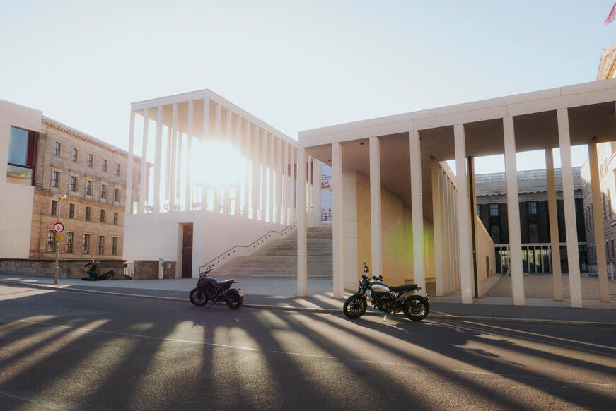 Motorcycles in front of an architectural building at sunset