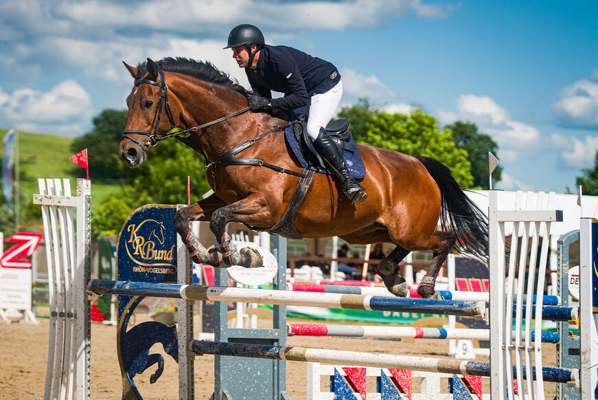 Show jumper with horse over obstacle