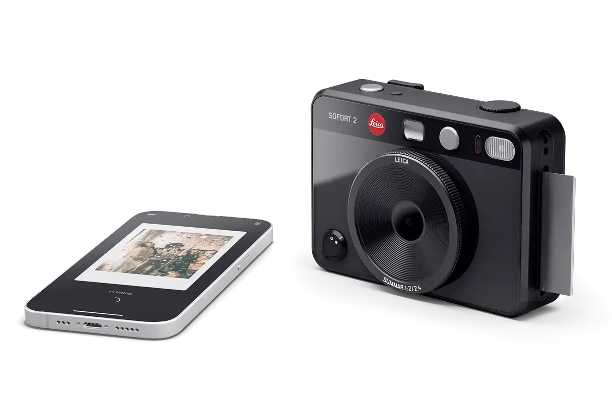 Leica Sofort 2 black beside mobile phone.