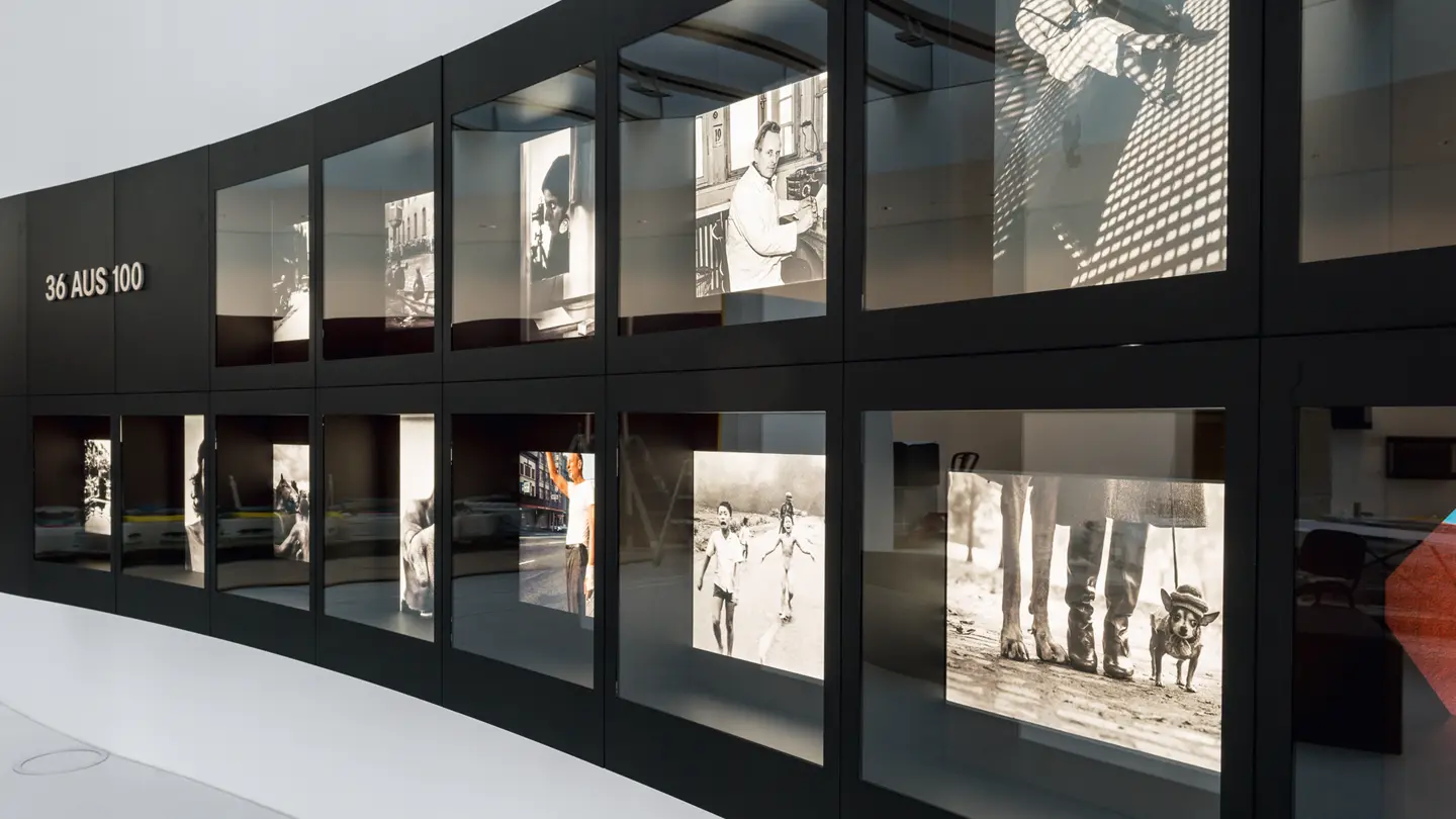 An exhibition of black and white photographs of famous events, presented in two curved rows.