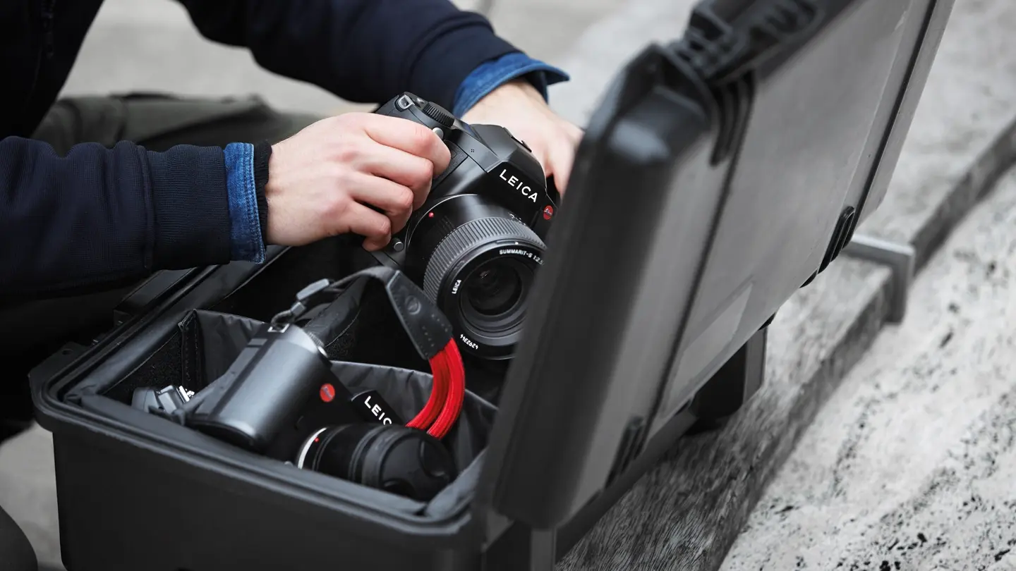 Close-up of a person taking a Leica camera out of a camera case