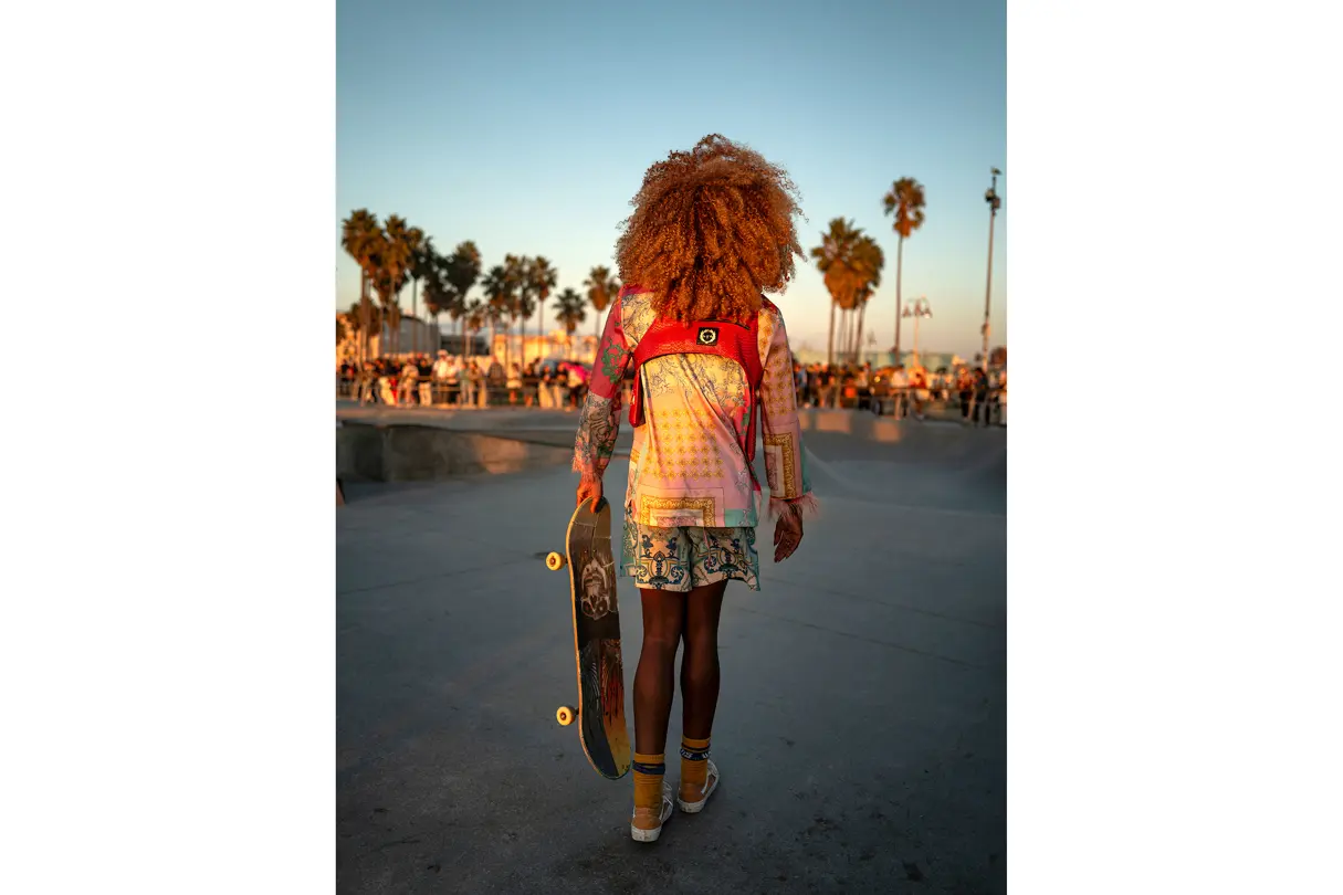 Skateboarder with afro at sunset in the skatepark.