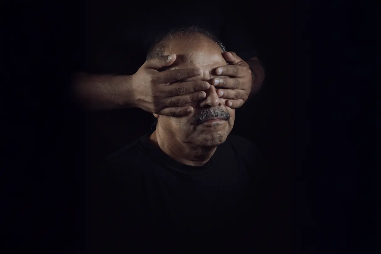 Hands cover man's eyes from behind