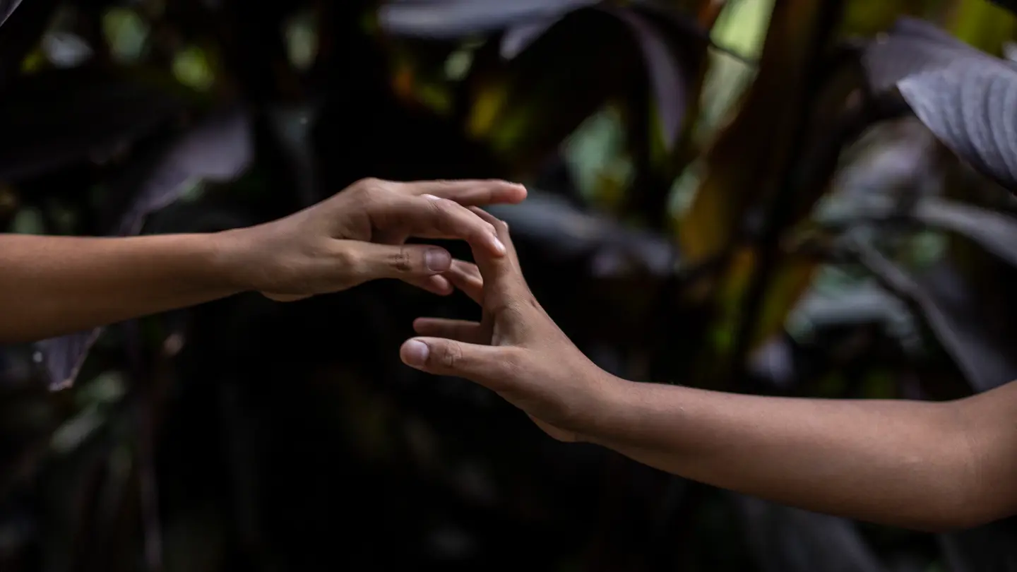 Two hands reach for each other.