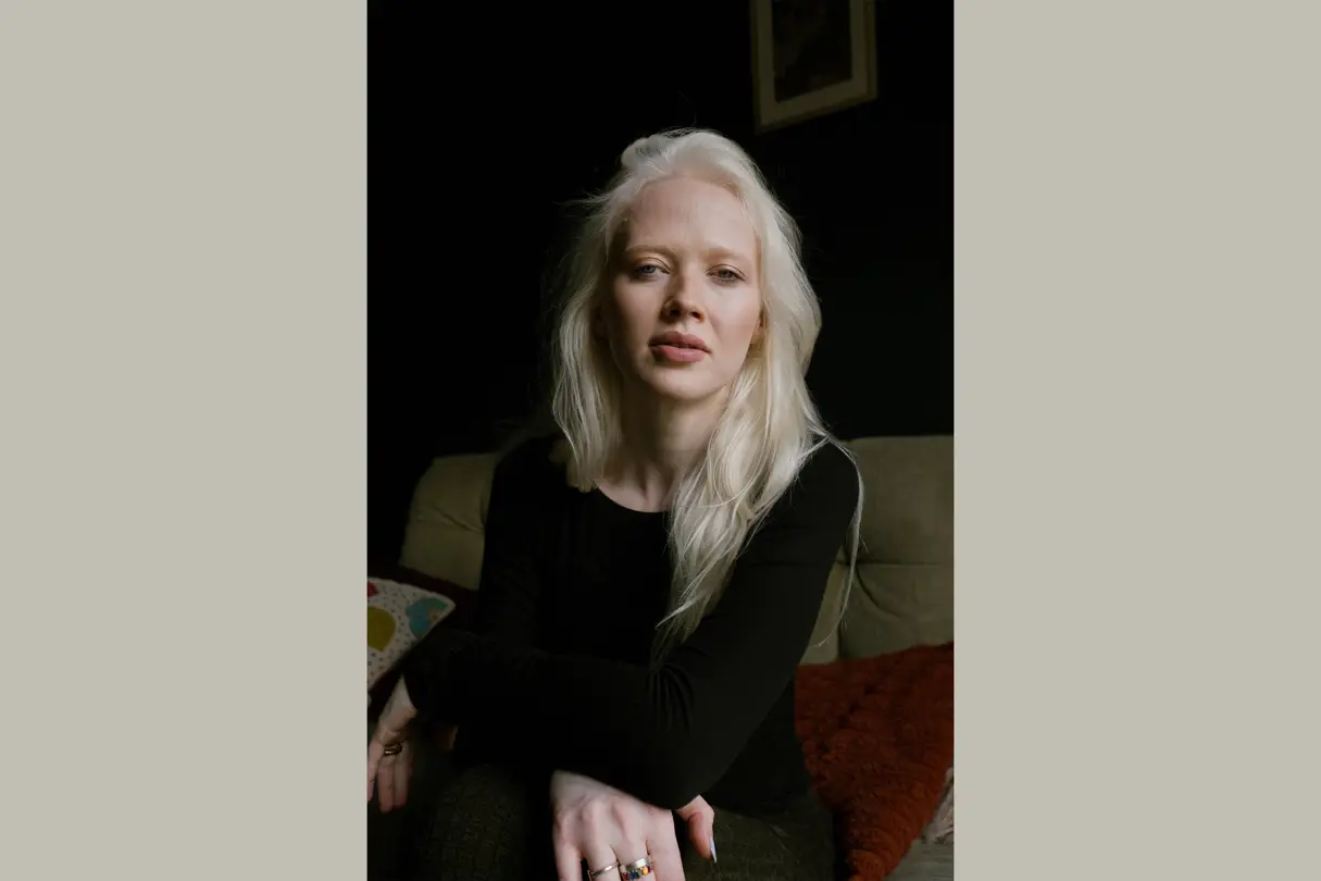 Woman sitting, dressed in black and long light blonde hair