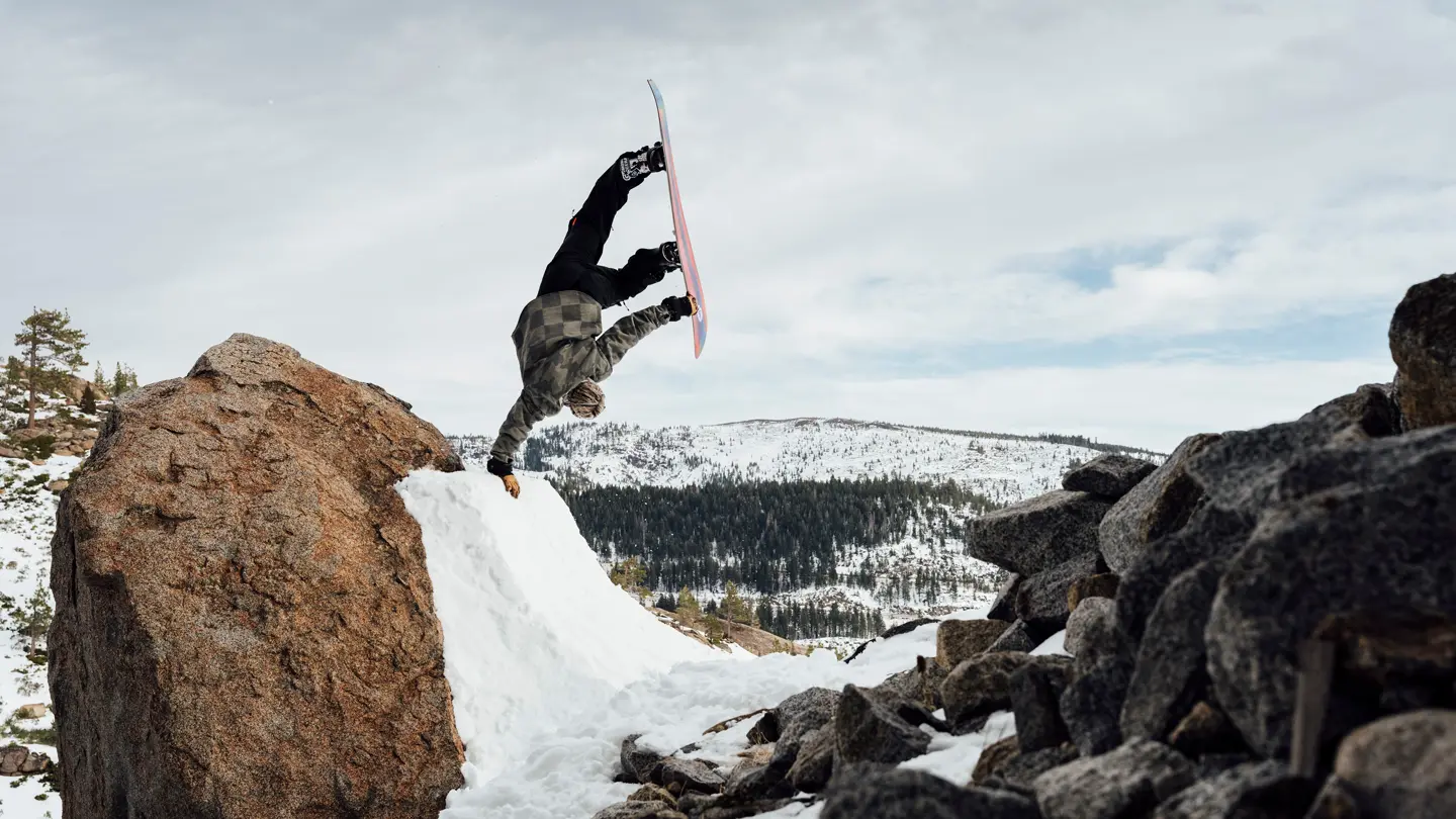 Snowboarder does a one-armed handstand on a ramp in the mountains