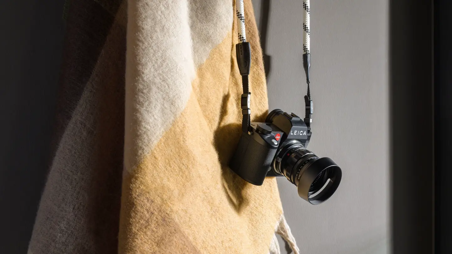 The Leica SL3 hangs on the corner of a chair.