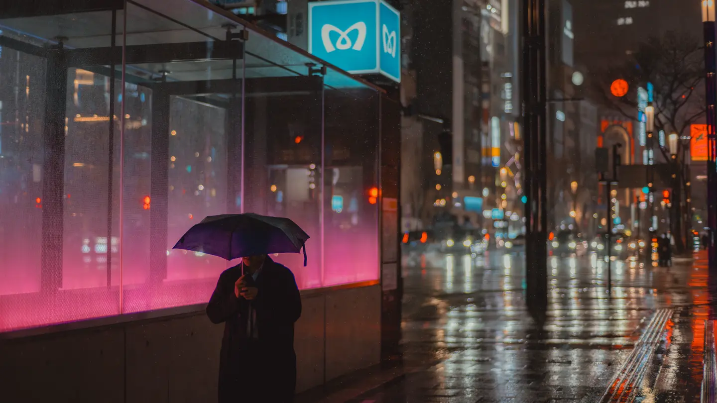Man walks through rainy streets with umbrella