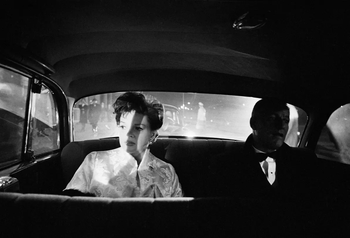 Black and white photograph of Judy Garland & Stanley Kramer sat on the backseat of a car.