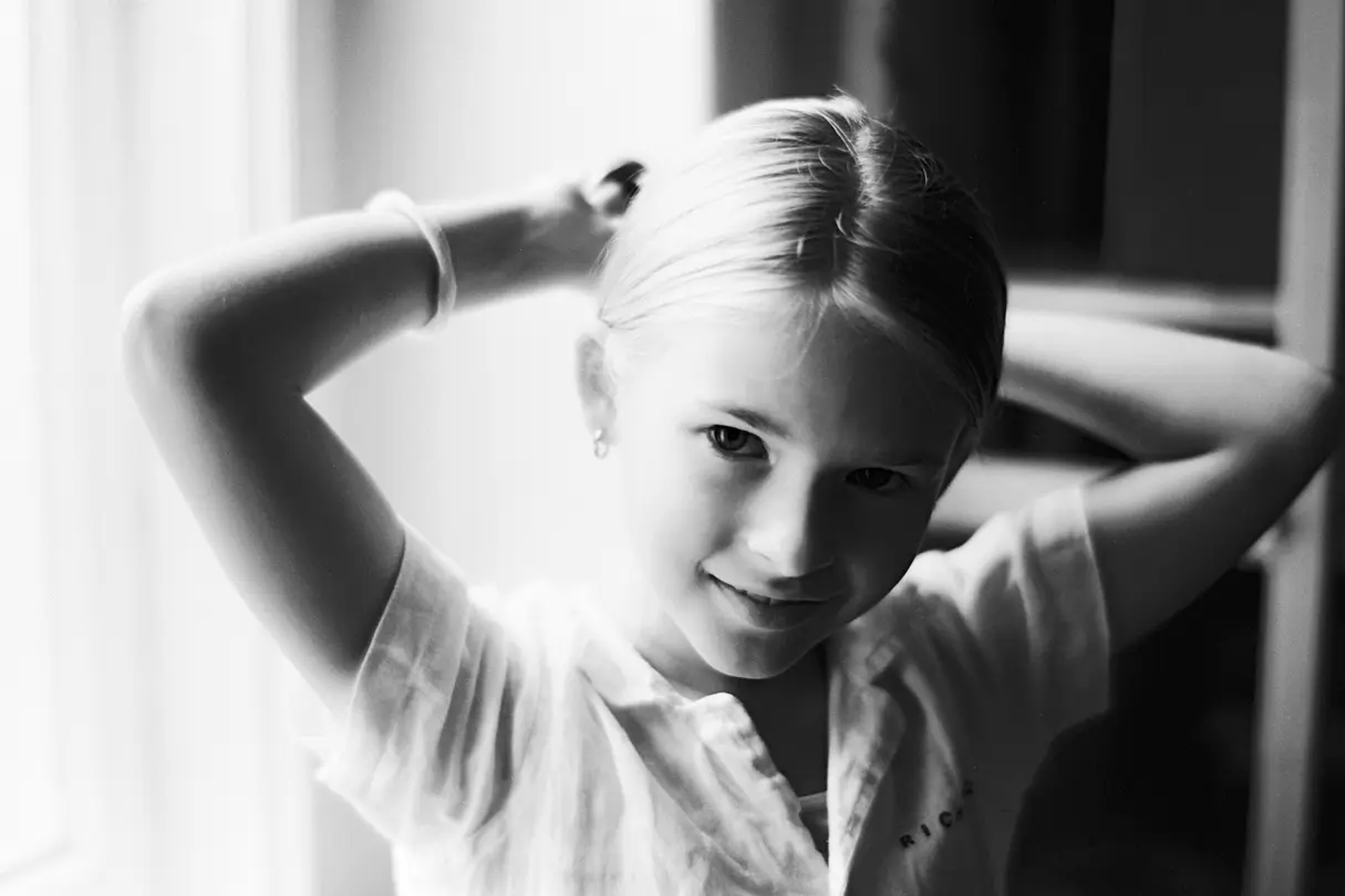 A girl makes herself a plait.