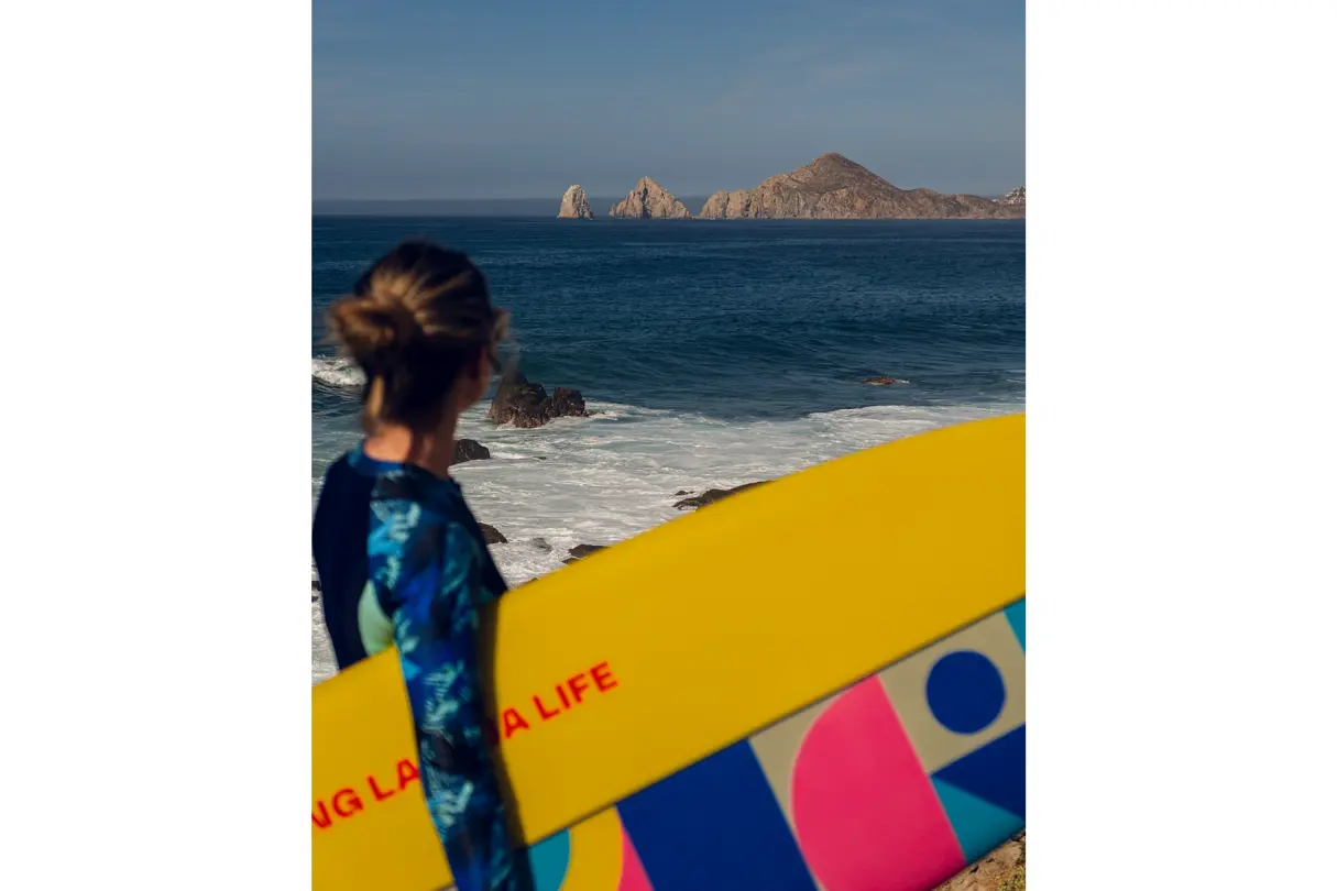 Woman with surfboard under her arm and the sea in the foreground