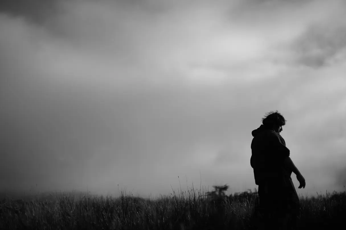 Black and white photograph of a man standing in a meadow