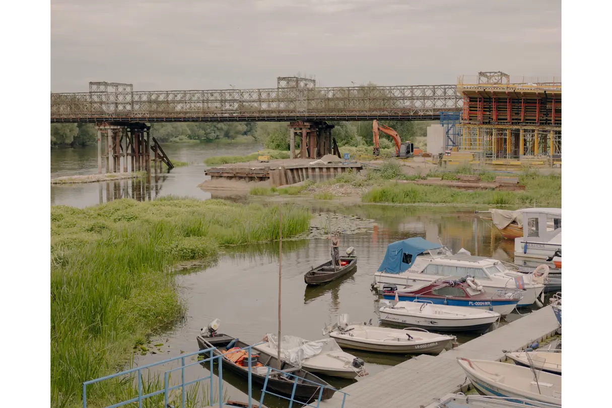 Man on a small boat in the background; a bridge is being built