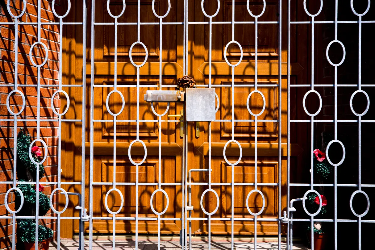 Locked metal door in front of a brown wooden door