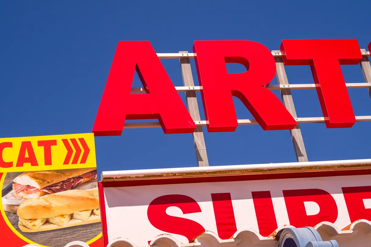 Red logo on a supermarket roof with blue sky in the background
