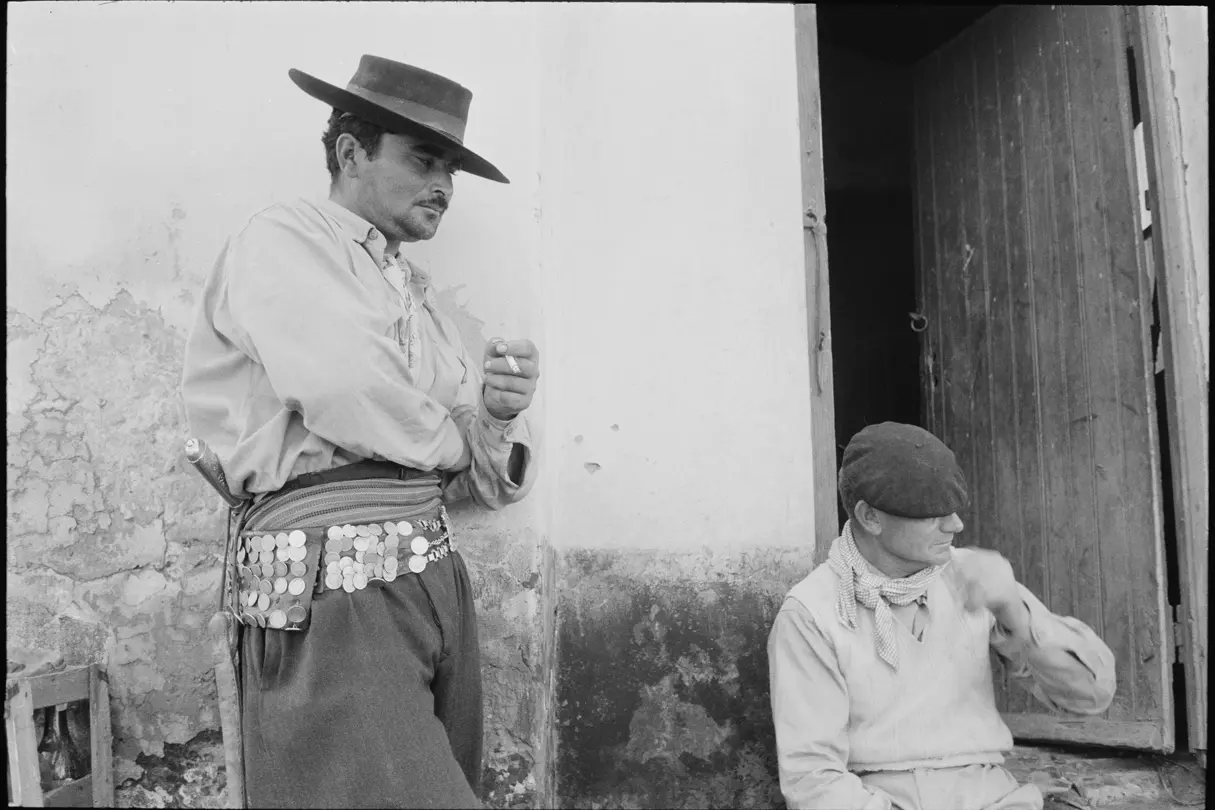 man standing with the coin belt and the other man sitting