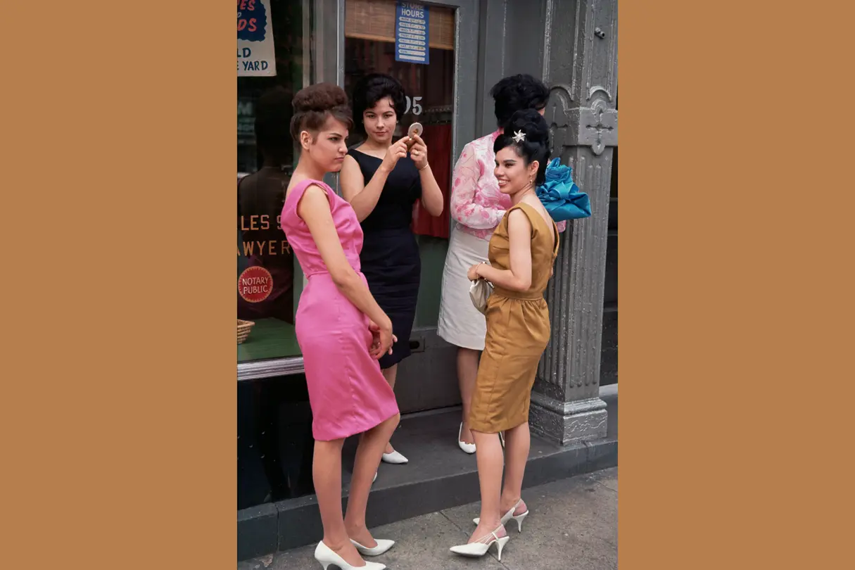 Four women standing in front of a shop with big windows.