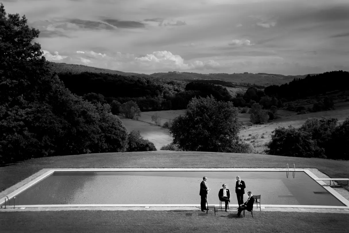 monochrom photography four men in suits in front of a pool on a large estate
