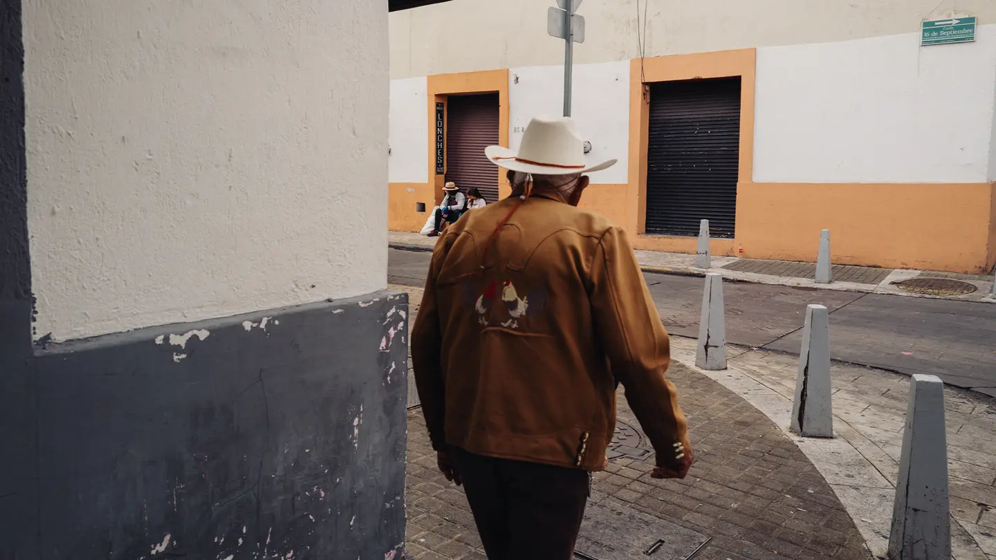 colour images of a man with brown coat in market in Mexico.