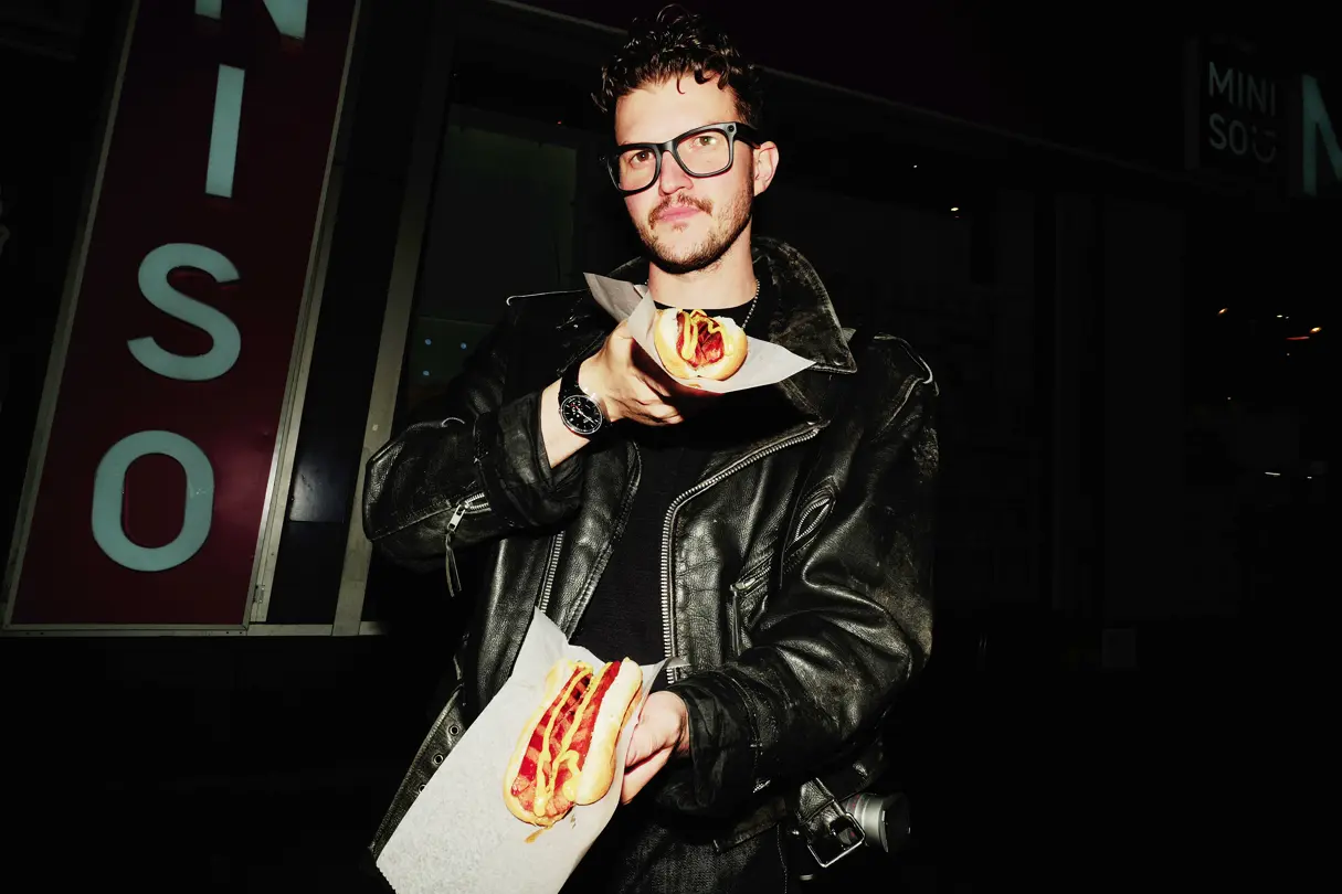 Man with a Leica ZM11 watch on his wrist and two hot dogs