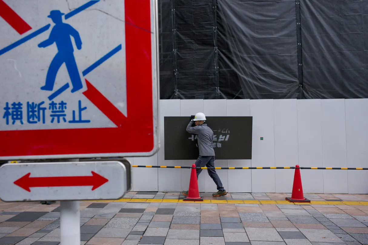Road signs and a construction worker carrying a sign in the background
