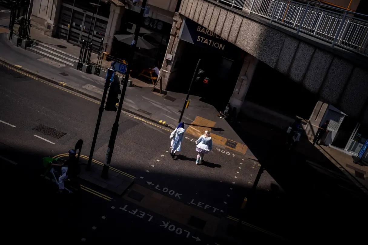 Two women in costumes cross a street