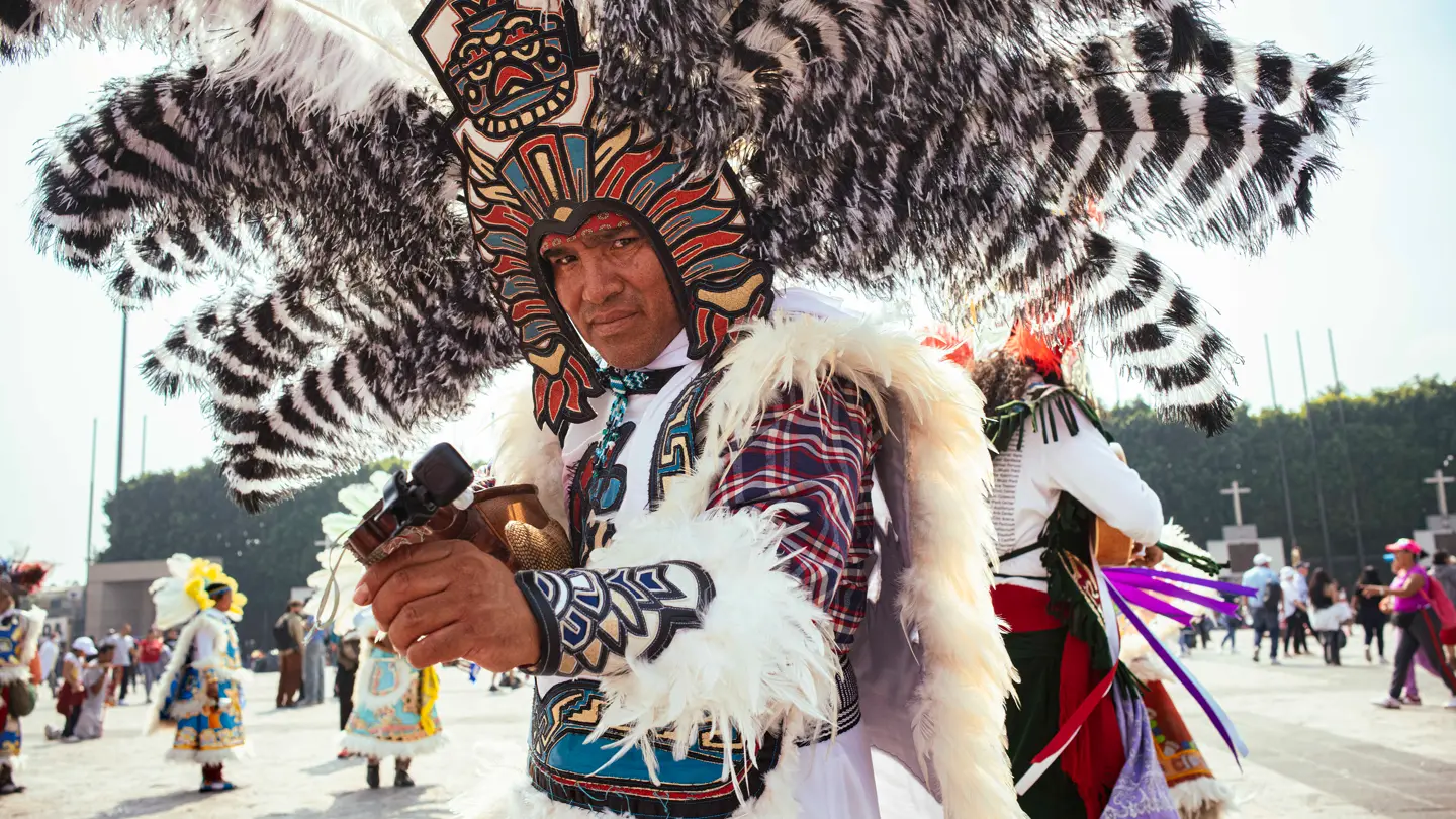 Colour image of a man wearing traditional costume with feathers.