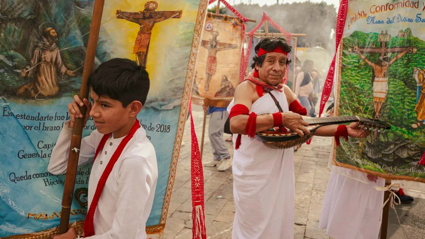 Colour image of a man wearing traditional costume with and a boy holding a flag.