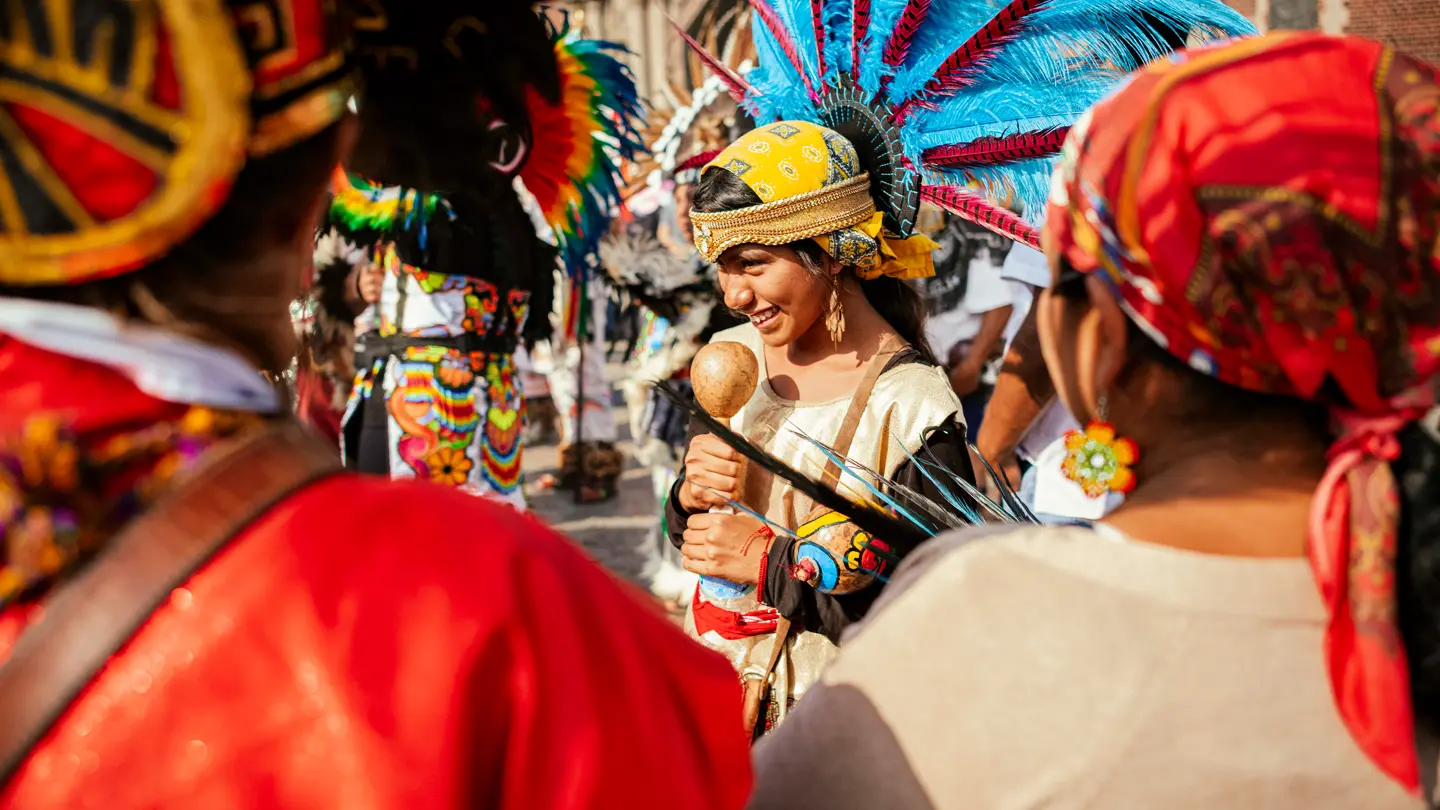 Colour image of a girl wearing traditional costume with feathered head piece.