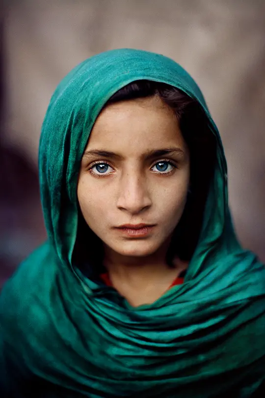 Portrait of a girl from Pakistan with a green scarf around her head and shoulders and bright blue eyes