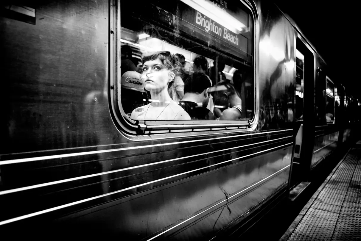 brunette woman sitting in subway black and white
